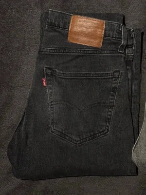 Svarta Levi's 511 slim jeans - Säljer ett par svarta Levi's 511 slim jeans med klassisk femficksdesign och brunt läderpatch bak i midjan. Jeansen har en smal passform och är tillverkade i mjuk denim med stretch. Perfekta för dig som gillar en clean och tidlös look.