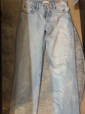 Ljusblå raka jeans  - Säljer ett par ljusblå jeans från Zara med rak passform och mid-låg midja. Jeansen har klassisk femficksdesign, knäppning med knappar och är gjorda i denim. Perfekta för en avslappnad och trendig look.💞