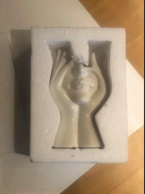 Vit keramikskulptur ansikte & händer - Unik vit keramikskulptur som föreställer ett ansikte inramat av två händer. Skulpturen är cirka 9 cm bred och har en blank finish. Perfekt som dekoration i hemmet eller som en cool inredningsdetalj på skrivbordet.