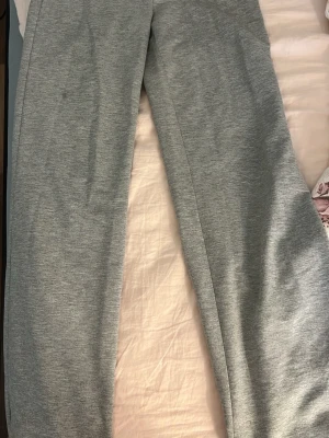Gråa mjukisbyxor med raka ben - Säljer ett par klassiska gråa mjukisbyxor i mjukt och skönt material. Byxorna har raka ben och resår i midjan för extra komfort. Perfekta för chill dagar hemma eller när du vill ha det bekvämt. Passar till det mesta och är superenkla att matcha.