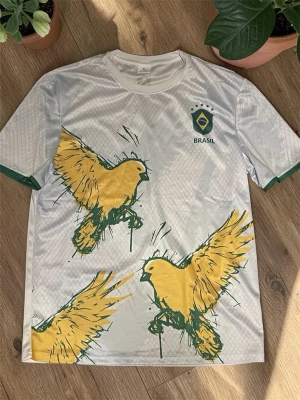 Vit Brasil t-shirt med gula fåglar - Snygg vit t-shirt med Brasil-logga på bröstet och stora gula fåglar i grafiskt tryck över hela framsidan. Gröna detaljer vid ärmslut och cool sportig vibe. Perfekt för dig som gillar unika prints och vill sticka ut.