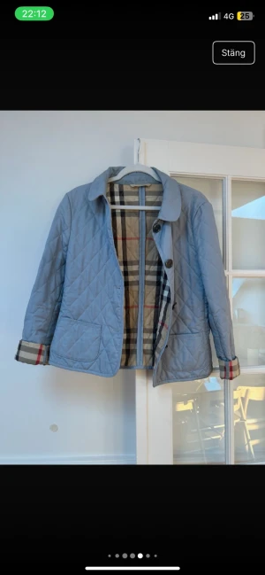 Ljusblå quiltad cardiganjacka Burberry - Snygg ljusblå quiltad cardiganjacka från Burberry med klassiskt rutigt foder och stora knappar framtill. Jackan har två framfickor och uppvikta ärmslut med Burberrys ikoniska mönster. Perfekt för dig som vill ha en stilren och tidlös look.