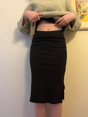 Svart ribbad långkjol med slits - Säljer en svart långkjol i ribbad stretchig kvalitet. Kjolen har en smal passform och en liten slits på sidan för extra rörelsefrihet. Perfekt att styla med en croppad tröja eller oversized hoodie. Jag säljer i s men massor även m även om det står st 152