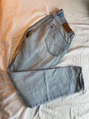 Levi's ljusblå raka jeans - Säljer ett par klassiska ljusblå jeans från Levi's med rak passform och femficksmodell. Jeansen har en ikonisk läderpatch bak i midjan och den röda Levi's-taggen på bakfickan. Tillverkade i slitstark denim, perfekta till vardagslooken.