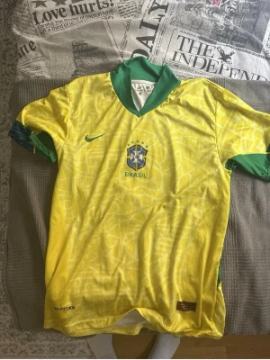 Brasilien Neymar Jr matchtröja Nike - Gul Brasilien fotbollströja från Nike med gröna detaljer, Neymar Jr och nummer 10 på ryggen. Officiellt förbundsmärke på bröstet och snygg krage. Tillverkad i lätt och ventilerande material, perfekt för träning eller match.