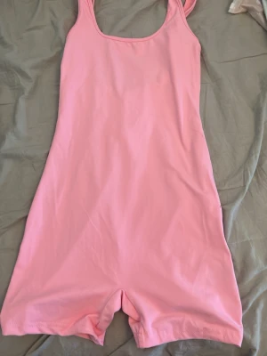 Rosa ärmlös jumpsuit i bomull - Supersöt rosa jumpsuit med ärmlös design och korta ben. Och den har öppen rygg