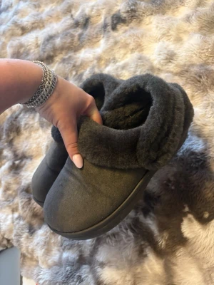 Mörkgrå fluffiga Crocs tofflor - Säljer ett par mörkgrå tofflor från Crocs med mjukt och fluffigt foder. De har en rund tå och en enkel slip-in design. Har använts ute ca 2 gånger köpt på zalando 