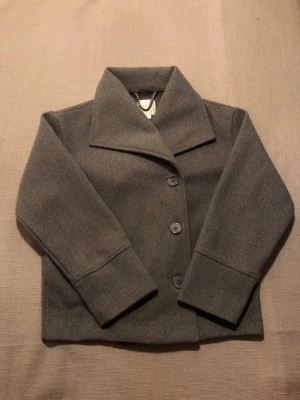Vår jacka/kappa från Gina tricot i storlek XS. - Super snygg grå kappa/jacka med knappar från Gina tricot till våren, i storlek XS. Säljer tyvär denna jacka för att den är för liten för mig.