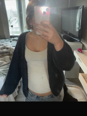 Mörkblå fluffig kofta - Mysig mörkblå kofta med fluffig textur och öppen front. Koftan har långa ärmar och en avslappnad passform som gör den enkel att slänga på över en topp eller t-shirt. Perfekt för att hålla värmen under kyliga dagar. Storlek xs/s