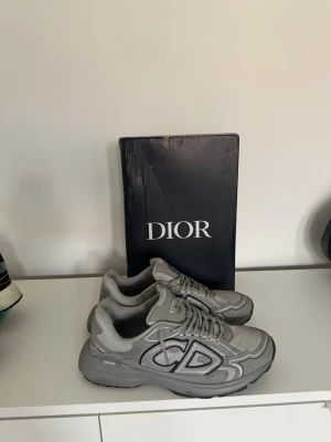 Grå B30 sneakers - Snygga grå B30 sneakers med mesh och läderdetaljer. Skorna har en chunky sula och stora reflekterande CD på sidan. Perfekta för dig som gillar trendiga sneakers med sportig vibe.