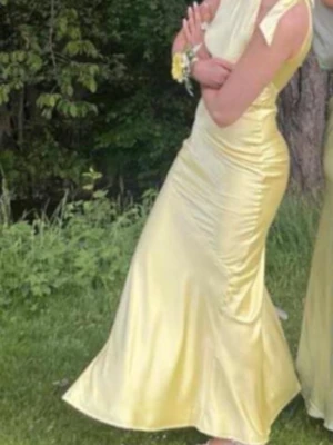 Balklänning i ljusgul - Säljer ni min älskade balklänning! I mycket bra skick!! Elegant ljusgul långklänning i glansigt satinmaterial med halterneck och figurnära passform. Jag är 169 cm lång, (sista bilden är inte min) 