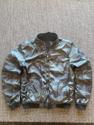 Woolrich windbreaker insideout modell - Säljer en vändbar vindjacka med grått camo-mönster på ena sidan och enfärgad grå på andra. Passsar perfekt nu till våren och sjukt fett modell. Obs kan även gå ner lite i pris vid snabb affär 🙌😊