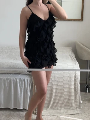 NA-KD black ruffle mini dress  - Svart NA-KD mini dress med volanger och tunna band. Superfin på kroppen och perfekt till fest, middag eller semester. Väldigt feminin och Pinterest/coquette vibe. Mycket bra skick