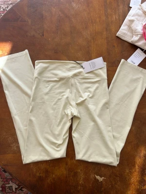 Gula leggings från Casall - Snygga och mjuka leggings från Casall i en ljusbeige färg. De har hög midja och är tillverkade i ett stretchigt material som sitter skönt mot kroppen. Perfekta för träning eller chill dagar. Diskret Casall-logga broderad baktill i midjan.
