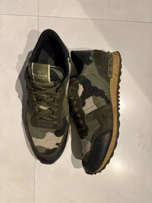 valentinos rockrunners gröna  - Snygga valentinos rockrunners med coolt kamouflagemönster i gröna och svarta toner. Skorna har detaljer i mocka och läder. Perfekta för dig som vill sticka ut med en exklusiv streetstyle. 