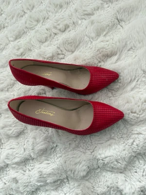 Röda pumps med struktur - Inte från zara, köpts utomlands!! Snygga röda pumps från Jensen med spetsig tå och klack. Skorna har en cool strukturerad yta som ger extra attityd. Perfekta för dig som vill sticka ut med färg och stil. Insidan är ljus och klacken är smal och elegant.