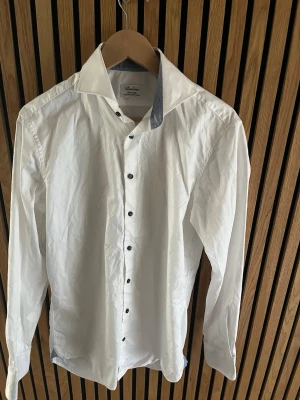 Vit skjorta med kontrastkrage - Klassisk vit skjorta från Stenströms med lång ärm och snygga mörka knappar. Skjortan har en kontrastfärgad insida på kragen som ger en modern touch. Tillverkad i bomull för en skön känsla och stilren look.