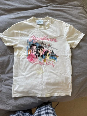 Vit Casablanca t-shirt  - Vit t-shirt från Casablanca med färgglatt tryck framtill som visar stadsmotiv och text i rosa och rött. Klassisk passform med rund hals och korta ärmar. Perfekt för dig som gillar streetstyle och unika prints.