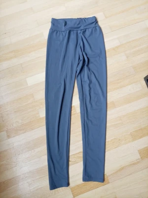 Blå höga midjeleggings - Mörkblå leggings med hög midja och stretchigt material. De har en enkel, slät design utan synliga loggor eller detaljer. Perfekta för en avslappnad och bekväm stil.