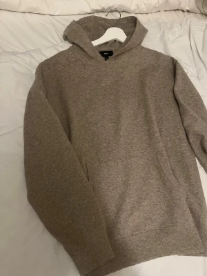 Beige hoodie  - Mysig beige hoodie från NEXT i storlek L. Klassisk modell med huva och känguruficka framtill. Tillverkad i mjukt material som känns skönt mot huden. Perfekt för en avslappnad och stilren look.
