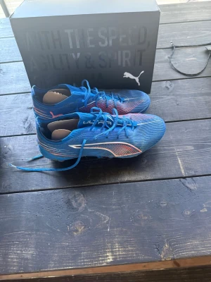 Blåa Puma Ultra fotbollsskor - Säljer ett par blåa Puma Ultra fotbollsskor med vita och röda detaljer. Använda men ändå i gott skick!
