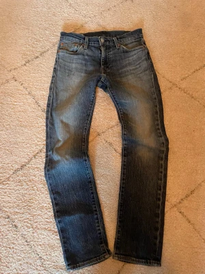 Levi's  jeans - Klassiska blå jeans från Levi's med rak passform och fem fickor. Jeansen har en snygg tvätt med lätt slitning och detaljer som synliga sömmar och läderpatch bak i midjan. Perfekta för en avslappnad och stilren look.