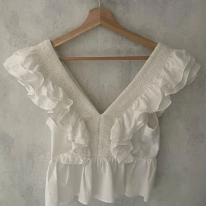 Snygg volang topp - Säljer denna superfina vita topp med volangdetaljer 🤍✨ Perfekt till fest, semester eller sommar outfits! Väldigt smickrande passform och så fin tillsammans med kjol eller jeans. Använd fåtal gånger och fortfarande i jättefint skick 🌸  Storlek: 36 (passar även 34) Hör av dig för eventuella frågor 💌