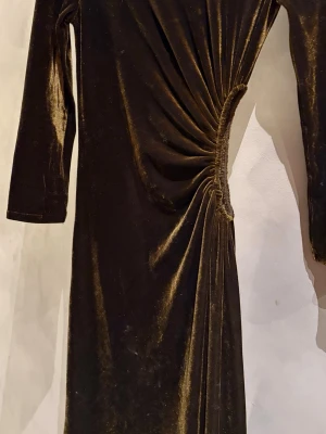 Maxiklännng från H&M EDITION  - Helt oanvänd långklänning i mörk khakigrön färg med  cut-out i midjan med rynk. Passform tajt/slim