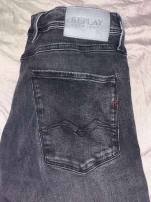 Grå jeans från Replay - Säljer ett par snygga grå jeans från Replay med klassisk femficksdesign och raka ben. Jeansen har en diskret tvättad look och Replay-logga på bakfickan samt patch i midjan. Perfekta till en avslappnad stil och tillverkade i mjukt denimtyg dem är även i hyperflex slimfit anbas moddel 