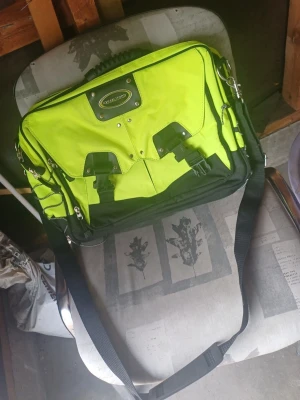 Väska - Cool datorväska i neongrönt och svart från Dellson. Väskan har flera fack, justerbar axelrem och detaljer i metall. Tillverkad i slitstark textil med praktiska spännen framtill. Perfekt för dig som vill sticka ut med din tech-stil.