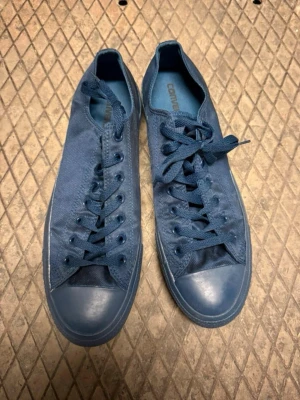 Blå Converse sneakers i tyg 46 - Snygga blå Converse sneakers i lågt modell med klassisk design. Skorna har ovandel i canvas, tåhätta i gummi och matchande blå skosnören. Perfekta för dig som gillar en clean och stilren look. Storlek 46