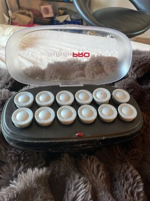 Babyliss värmerullar för hår - Babyliss värmerullar i svart och silver med genomskinligt lock. Perfekt för att skapa snygg blow out look. Kommer i ett smidigt fodral med plats för 12 rullar.