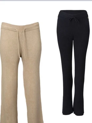  ribbade mjukisbyxor från Pernilla Wahlgren design - Svarta ribbade mjukisbyxor från Soft Pernilla Wahlgrens märke. Byxorna är stickade i ett mjukt material och är väldigt stretchiga. Även har en liten guldfärgad logodetalj med en ananas vid fickan. Perfekta för en avslappnad och trendig look.