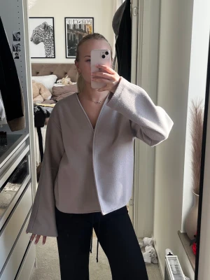 Beige Kappahl kappa - Kort kappa ifrån Kappahl, kappan har en knapp som stänger den snyggt.