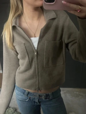 Beige ziptröja med krage - Snygg beige ziptröja med krage och två stora fickor framtill.