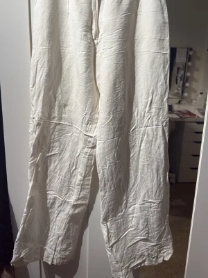 Vida vita linnebyxor - Säljer ett par vida linnebyxor i vitt med avslappnad passform och raka ben. Byxorna är tillverkade i ett luftigt linnetyg som ger en skön och sval känsla. Perfekta för en chill och stilren look.