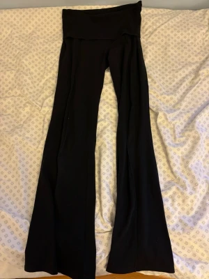 Svarta Yougapants - Säljer ett par svarta yougapants med utsvängda ben. Byxorna har en en snygg design med ett streck i mitten😻De är stretchiga och mjuka, perfekta för en trendig och bekväm look. Passar dig som gillar mode och vill ha något som sticker ut lite extra.