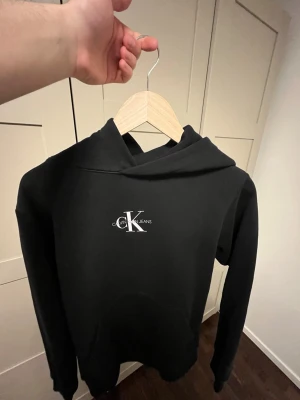 Svart hoodie från Calvin Klein - Svart hoodie från Calvin Klein Jeans kommer i storlek smal. 