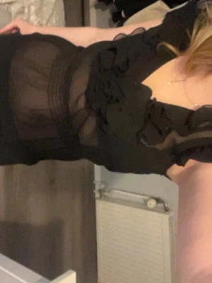 Svart transparent blus med volanger - Säljer en svart transparent blus med volangdetaljer och korta puffärmar. Blusen har en djup urringning och är gjord i ett tunt, lätt material som ger en luftig känsla. Perfekt för dig som gillar trendiga och feminina plagg.