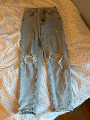 Ljusblåa jeans med hål💗 - Säljer ett par ljusblå perfect jeans med hål vid knäna. Jeansen har hög midja, raka ben och klassisk femficksdesign.🩵 Perfekta för en avslappnad och trendig look. Materialet är denim i bomull.💓💓