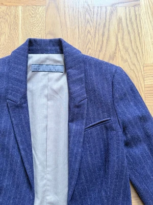 Ullkavaj Zara randig  - Snygg  kavaj från Zara Basic med diskreta vita ränder och lila ton. Klassisk passform med en knapp framtill, fickor och ljus innerfoder. Perfekt för en stilren look. Slits baktill. I mycket bra skick men för liten för mig 🥲 65% ull!