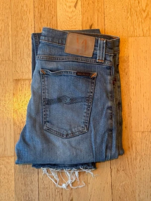 Blå jeans från Nudie Jeans W31 L34 - Hej! Säljer ett par nudie jeans i fint sick//jeansen har inga defekter (avklippta längst ner)  och är i storleken W31 L34//hör av er vid frågor! Vid snabb affär kan vi pruta lite🤝🤝