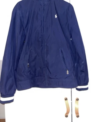 Ralph Lauren Windbreaker - Riktigt schysst windbreaker från Ralph Lauren. Använd ett fåtal gånger men skicket är ändå topp! Perfekt inför våren och går att matcha med det mesta! Skriv privat för mer bilder samt hur den sitter på osv. Inga defekter!