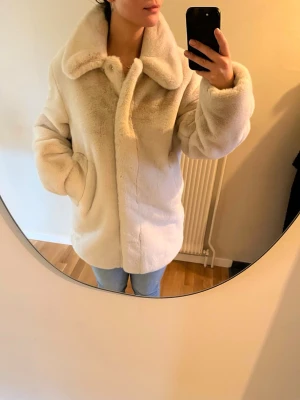 Beige fisk pälsjacka - storlek s - Varm och skön pälsjacka i supermjukt material från H&M  Hög krage, två fickor och knappar för stängning. Slutar strax under rumpan   Storlek S