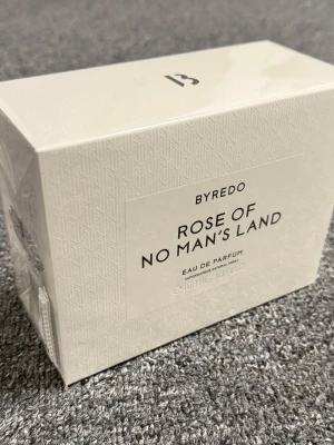 Byredo Rose of No Man's Land EdP - Byredo Rose of No Man's Land Eau de Parfum i elegant vit kartong med subtilt mönster. Doften är känd för sina fräscha och blommiga toner av ros. Flaskan rymmer 100 ml och är perfekt för dig som gillar exklusiva och moderna parfymer.