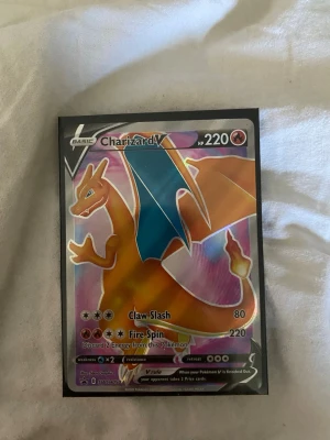 Charizard V Pokémonkort holo - Säljer ett Charizard V Pokémonkort med holografisk yta. Kortet har en färgstark design med Charizard i orange och blått, HP 220 och attacker som Claw Slash och Fire Spin. Perfekt för samlare eller Pokémon TCG-spelare.
