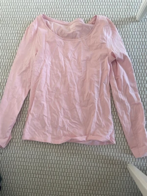Ljusrosa långärmad topp - En enkel och stilren ljusrosa långärmad topp med rund halsringning. Perfekt att matcha med jeans eller kjol för en avslappnad look. Tillverkad i mjuk bomull som känns skön mot huden.