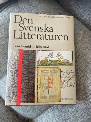Den Svenska Litteraturen - En bok om svensk litteraturhistoria, skriven av Lars Lönnroth och Sven Delblanc. Omslaget är beige med illustrationer av runsten, medeltida manuskript och konstverk. Perfekt för dig som vill fördjupa dig i svensk litteratur från forntid till frihetstid.