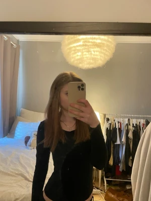 Svart långärmad body i sammet - Säljer en svart body med långa ärmar i mjuk sammet. Bodyn har en enkel, stilren design med rund halsringning och åtsittande passform. Perfekt att matcha med jeans eller kjol för en trendig look.