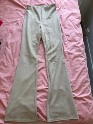 Beiga utsvängda byxor i mocka tyg från Stradivarius  - Snygga beiga byxor med utsvängda ben och hög midja. Tillverkade i ett mjukt material som ger en skön känsla och trendig look. 